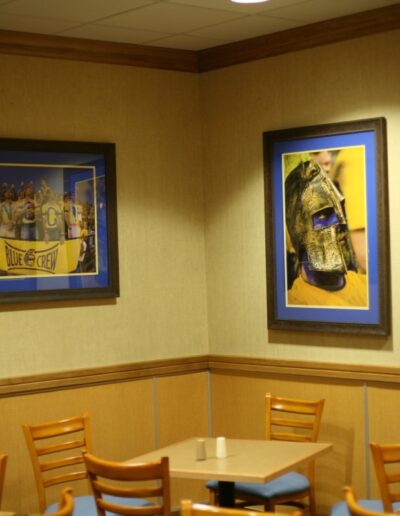 Wall art in a cozy cafe corner features sports-themed portraits in blue frames.